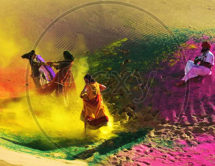 Two Girls And One Man Celebrating Holi, The Festival With Colors And Music