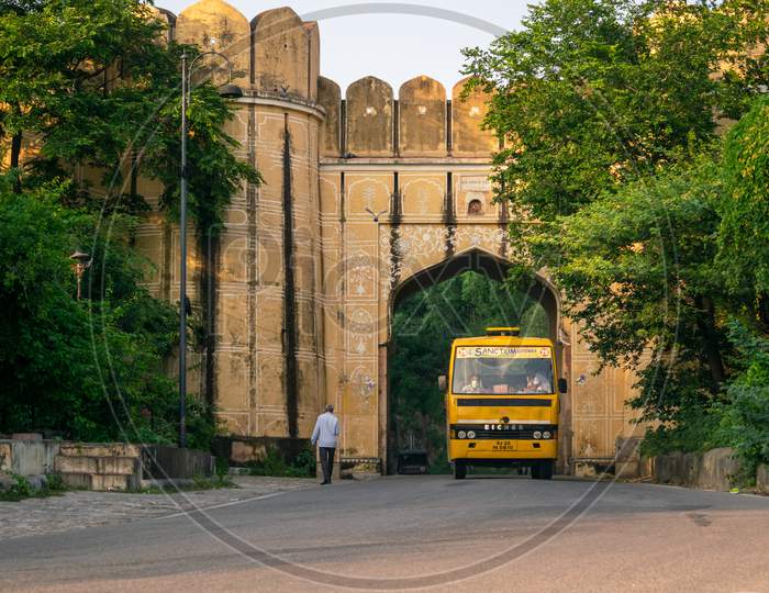 A Jaipur city bus moving on amer road and passing through an old gate
