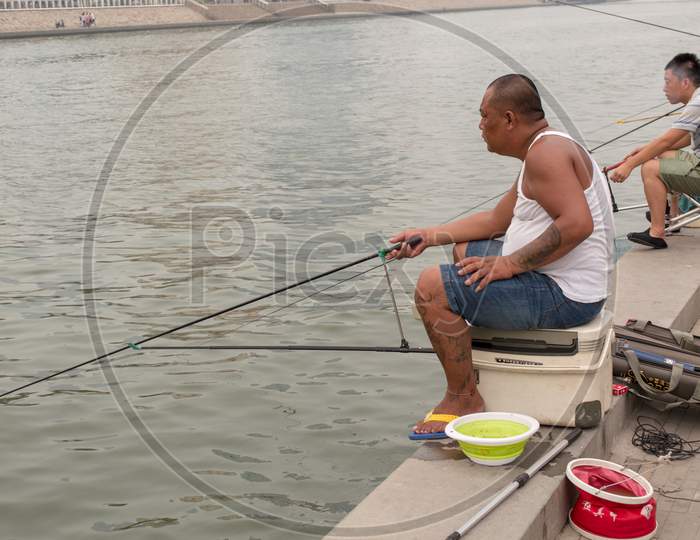 Fishermen Fishing On The Bank Of The Hai River In Tianjin, China