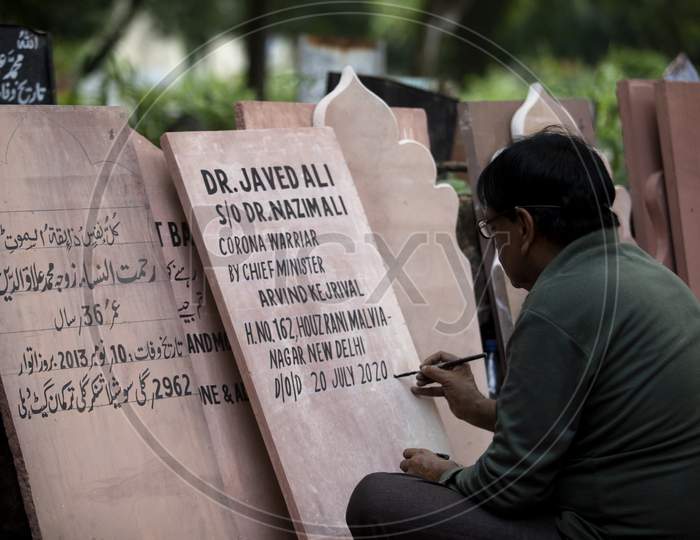 A tombstone maker engraves a tombstone of a Covid -19 victim near a graveyard in New Delhi, India, on September 14, 2020.