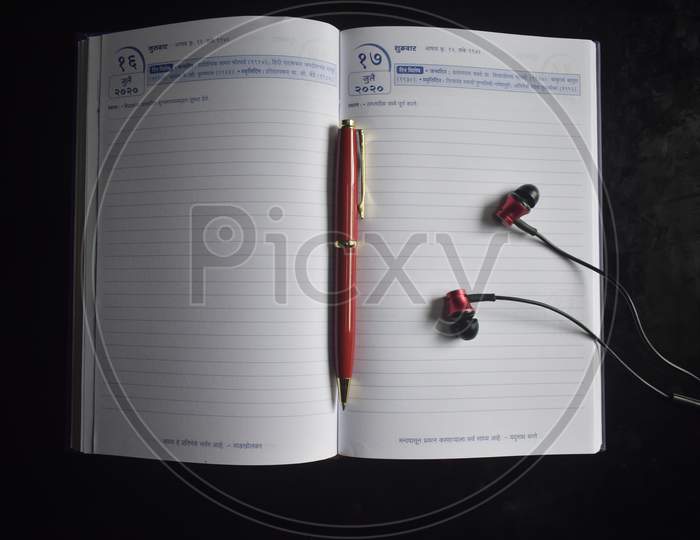 Photograph of diary with pen and earphone.