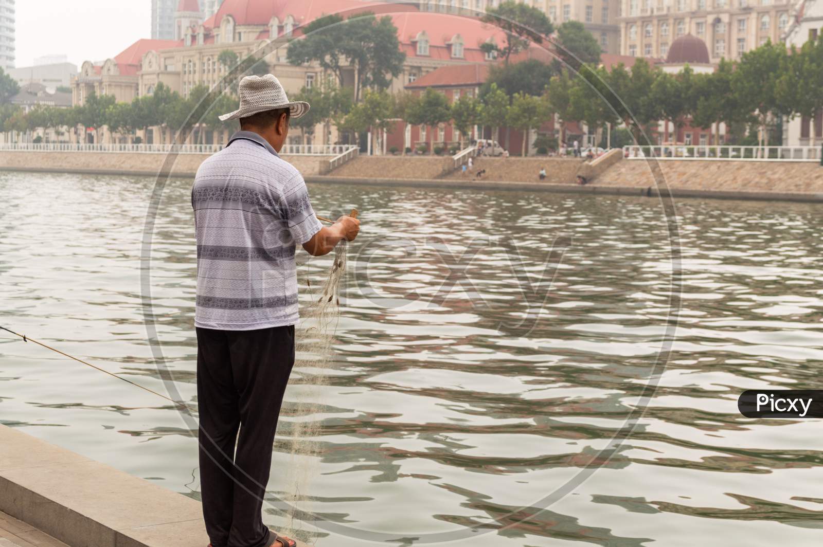 Fisherman Fishing On The Bank Of The Hai River In Tianjin, China