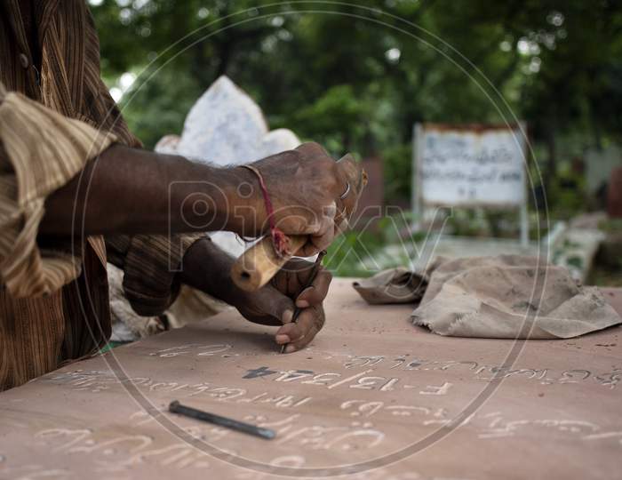 A tombstone maker engraves a tombstone of a Covid -19 victim near a graveyard in New Delhi, India, on September 14, 2020.