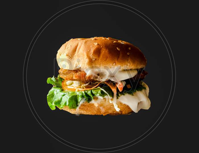 Fresh testy burger with tomatoes, Cheese ,Green lettuce, onion and salad isolated on black background .