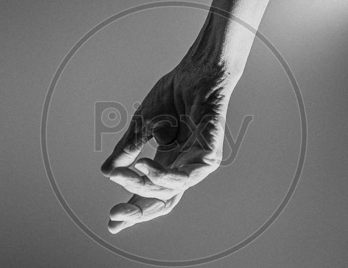 Old Hand Hangs From The Top Of The Image In Black And White