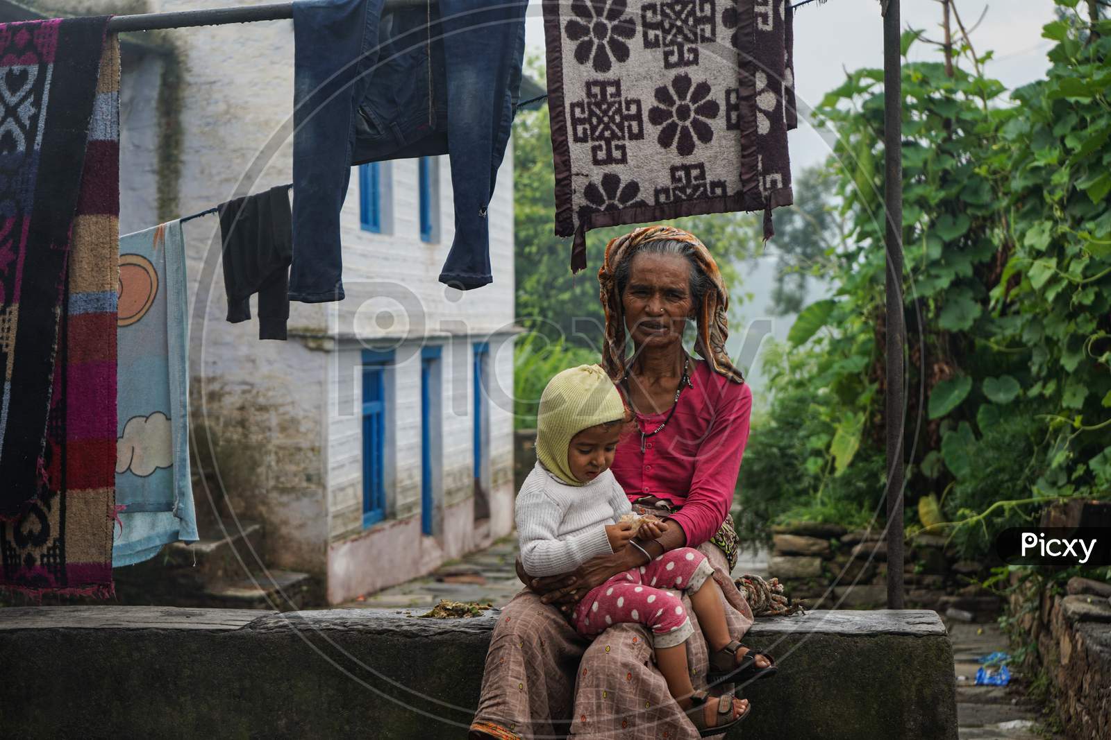 Almora, India - September 06, 2020: Portrait Of An Old Woman, Wearing Old Rugged Saree Holding A Kid In Her Lap.