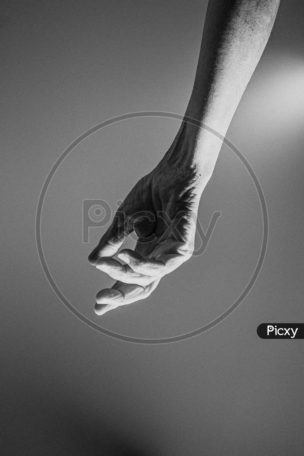Old Hand Hangs From The Top Of The Image In Black And White