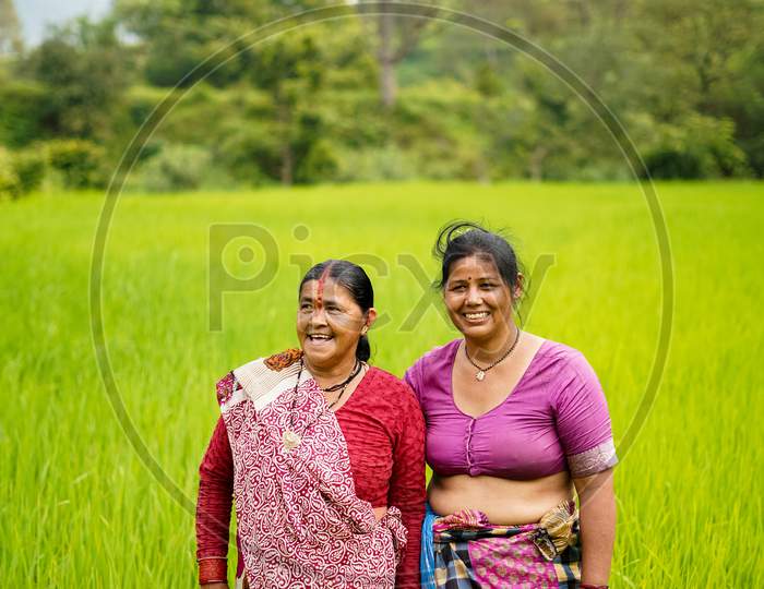 Almora, India - September 15, 2020: Old Indian Woman Farmers Standing In Working In The Green Fields, Smiling And Looking Into The Camera.