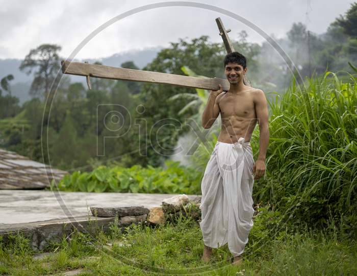 Happy Indian Farmer Standing With Wooden Plough In Rice Field