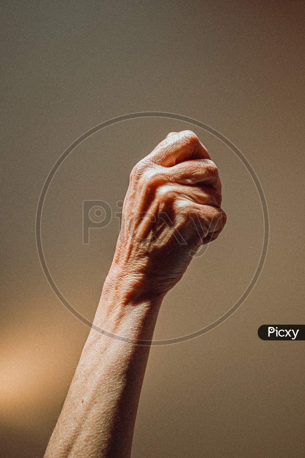 Old Woman Closed Hand Rising On Pastel Tones With Lights