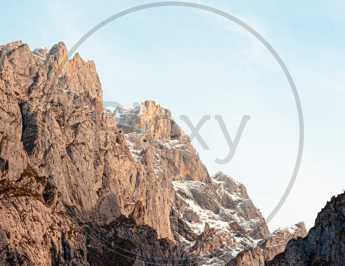 Giant Rocky Mountain On Pink And Meat Tones With A Bright Blue Sky Background