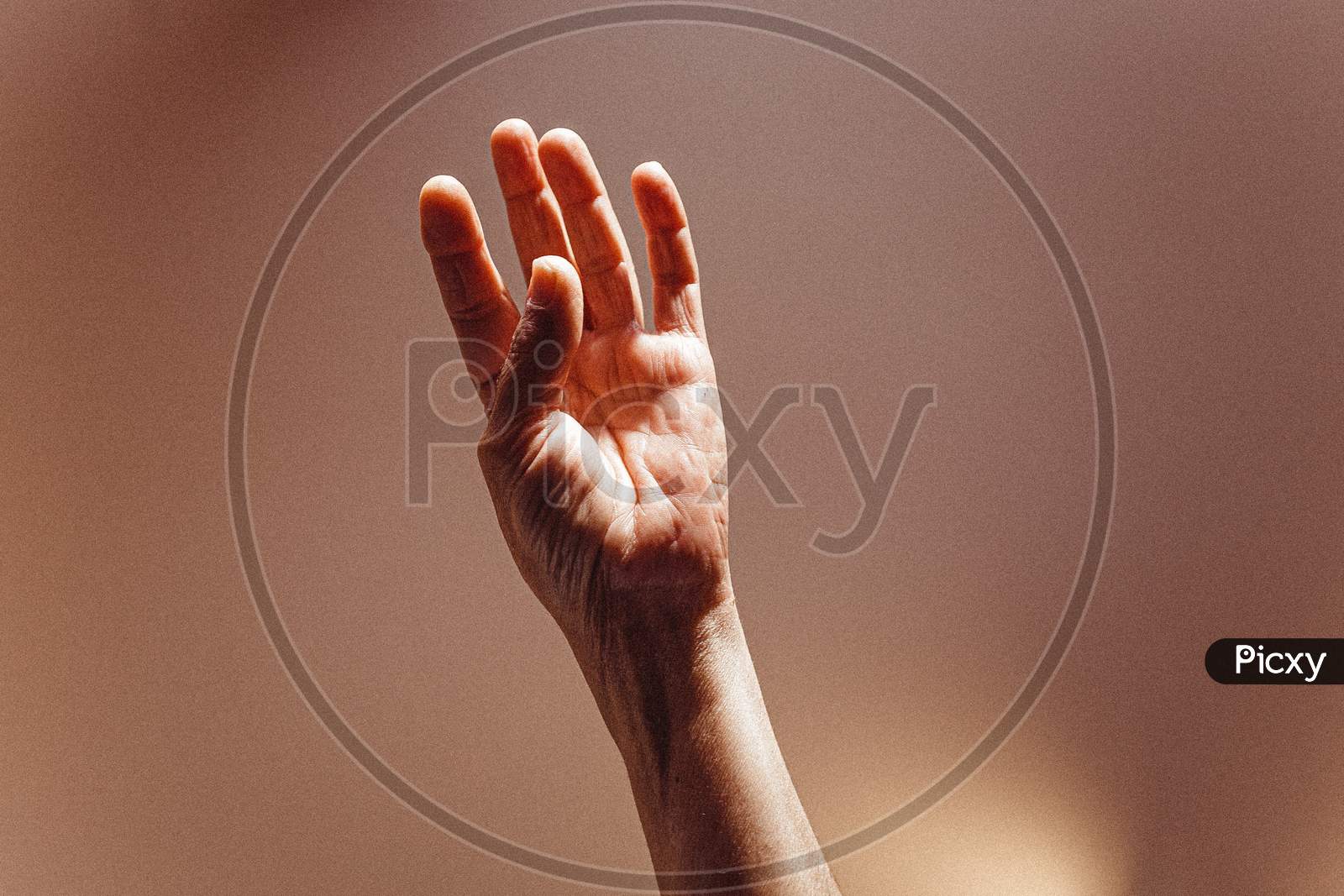 Old Woman Open Hand Rising On Pastel Pink Tones With Lights