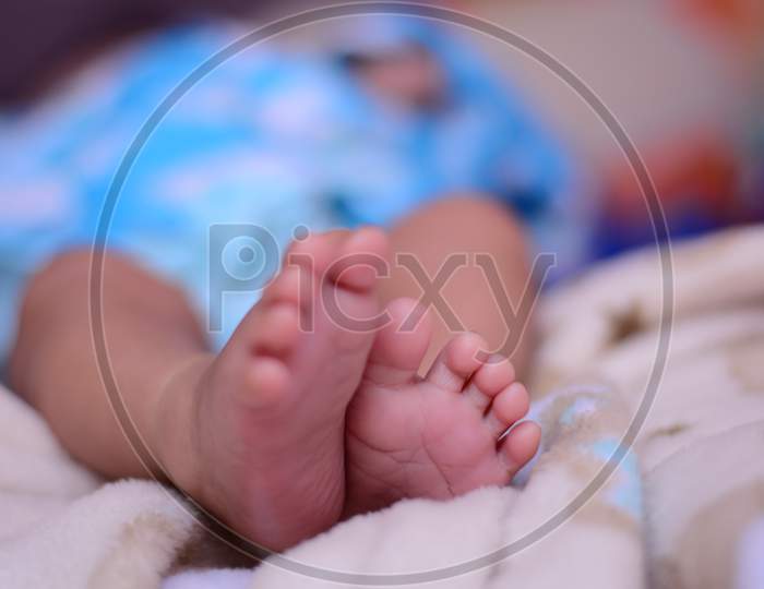 Tiny feet of a new born wrapped in a off white colored blanket