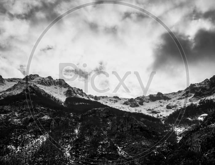 Dramatic Black And White Snowy Mountain With Strong Clouds Over It