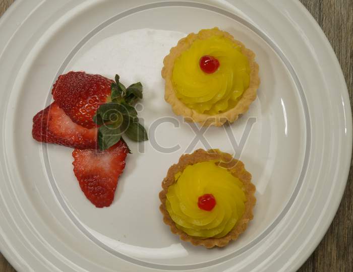 Tasty Strawberry Indian Cupcake With Cherry On The Top Decorated On White Plate