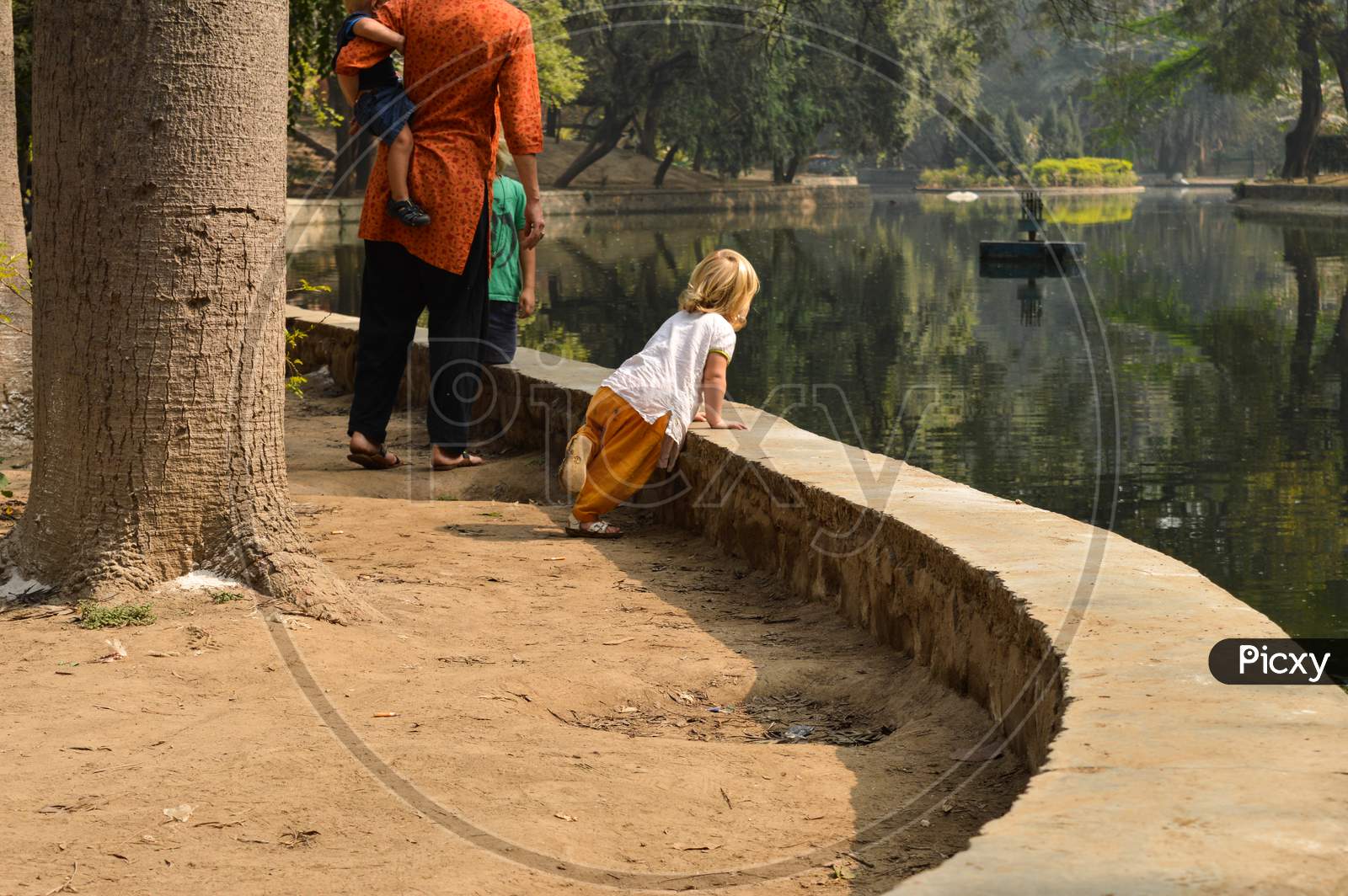 Two Child Siblings With Mom Looking For Fish At Pond Side At Lodhi Garden Park.