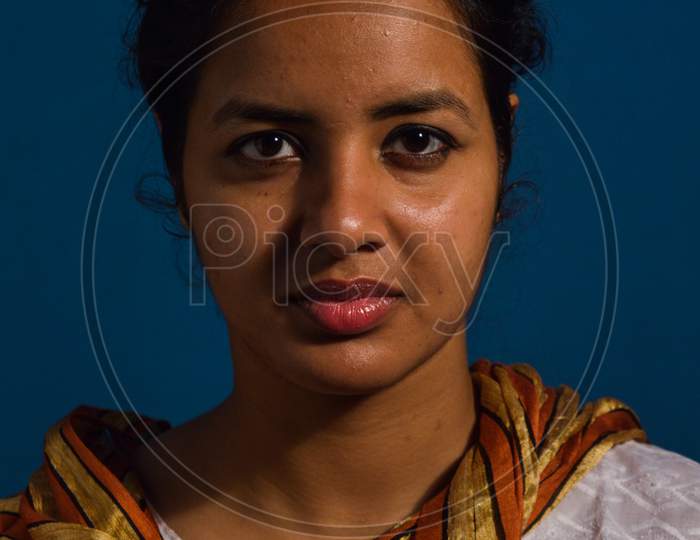 A Student Posing Like Sitter, Model At Classroom For Portfolio With Rembrandt Lighting System With Blue Background.