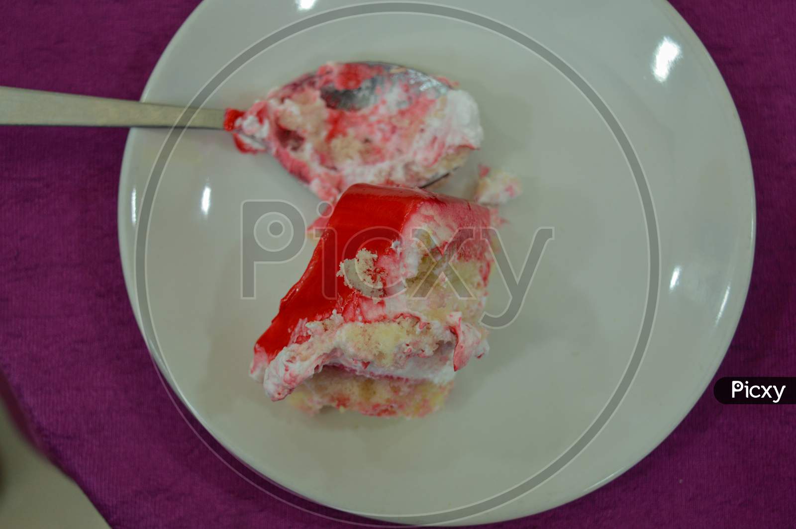A Beautiful Piece Of Strawberry Cake And Cream Serve On White Plate Isolated On Purple Table Cloth.