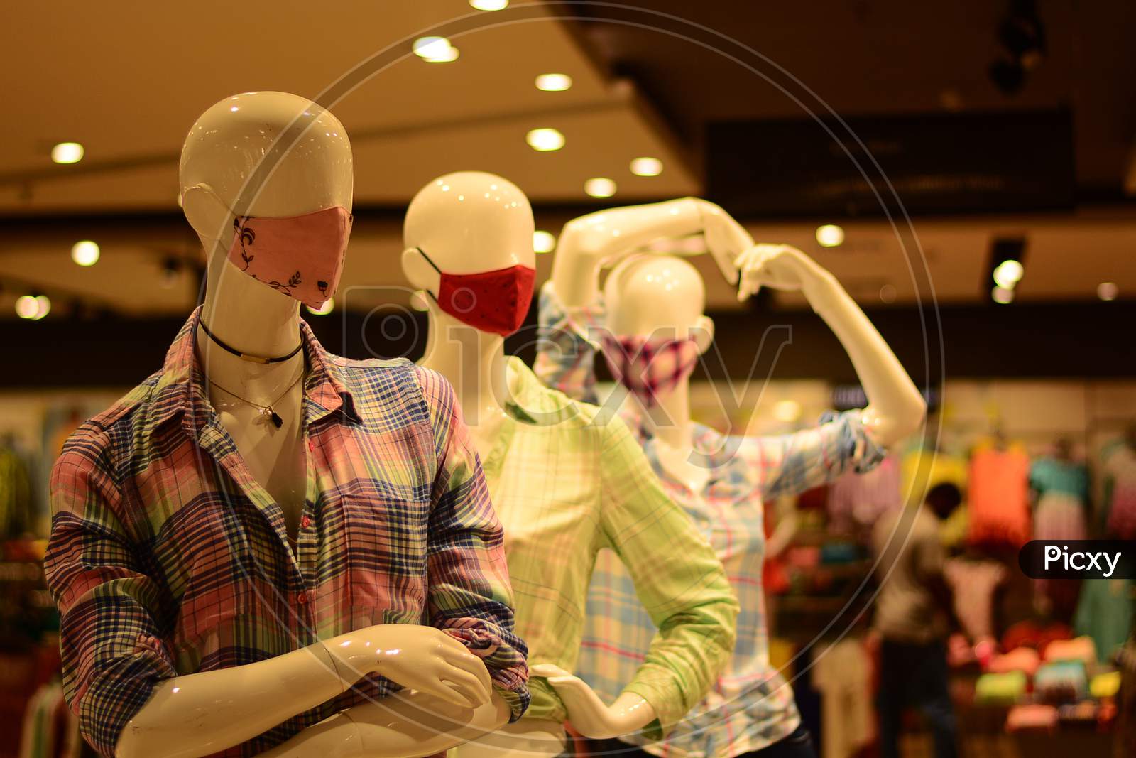 Three Masks Along With Fashion Garments Are Displayed Non Three Mannequins In A Garment Store