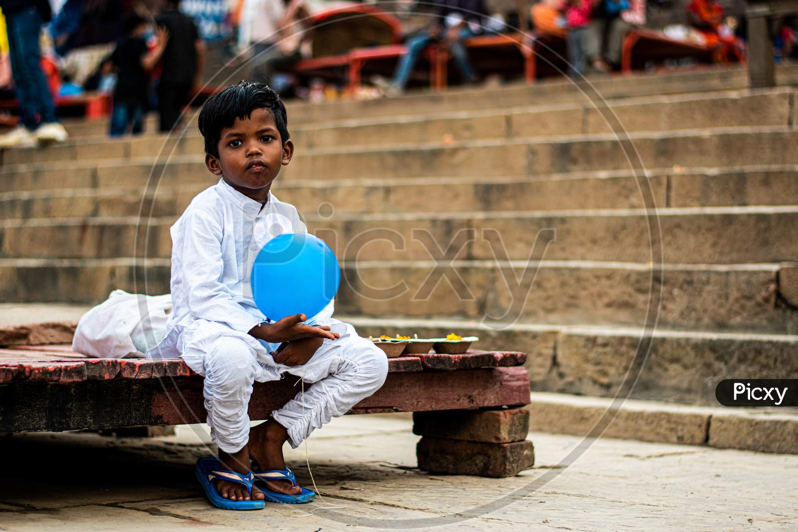 A cute little boy vending diya on assi ghat