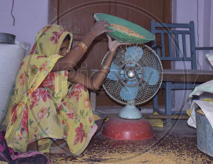 Rural Indian Woman Cleaning Grain At Home