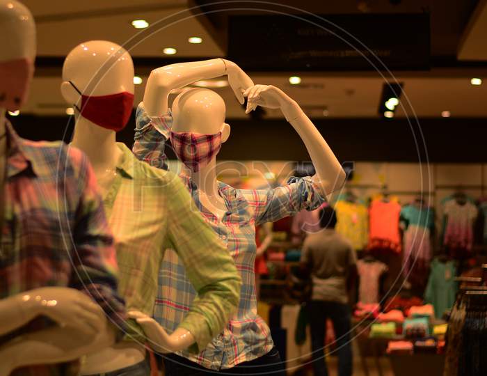 Three Masks Along With Fashion Garments Are Displayed Non Three Mannequins In A Garment Store