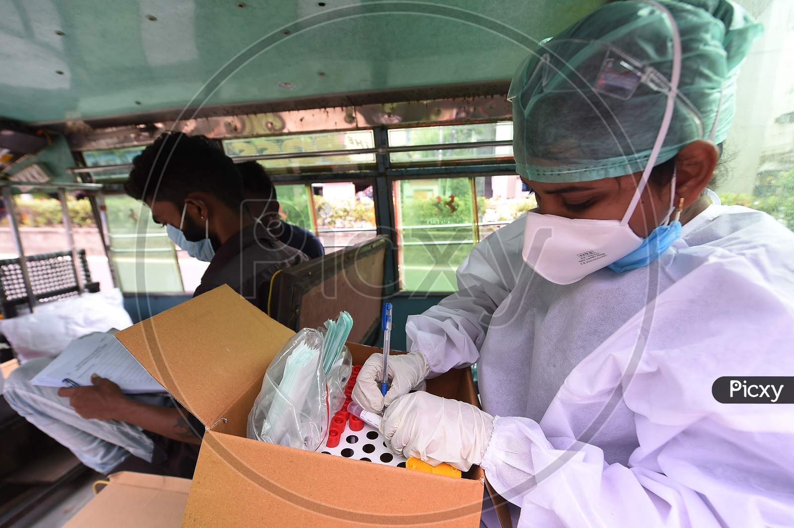 A Health Worker Arranges Tubes Containing Swab Samples In A Tray For Covid-19 Test At A Share Auto-Rickshaw As She Collects A Swab Sample From A Man To Test For The Covid-19 Coronavirus, Outside A Commercial Centre In Chennai On September 15.2020