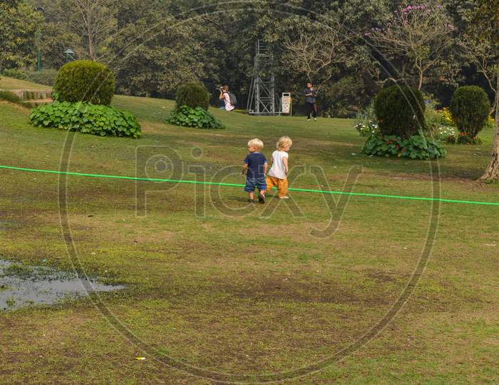 A Siblings Playing And Running At Park, Lawn At Winter Foggy Morning.