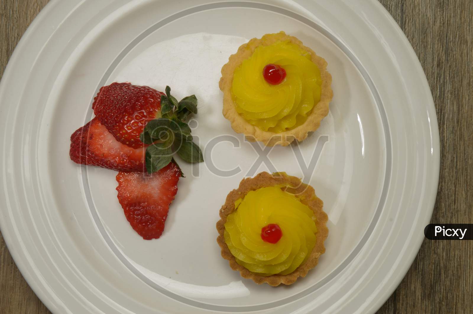 Tasty Strawberry Indian Cupcake With Cherry On The Top Decorated On White Plate