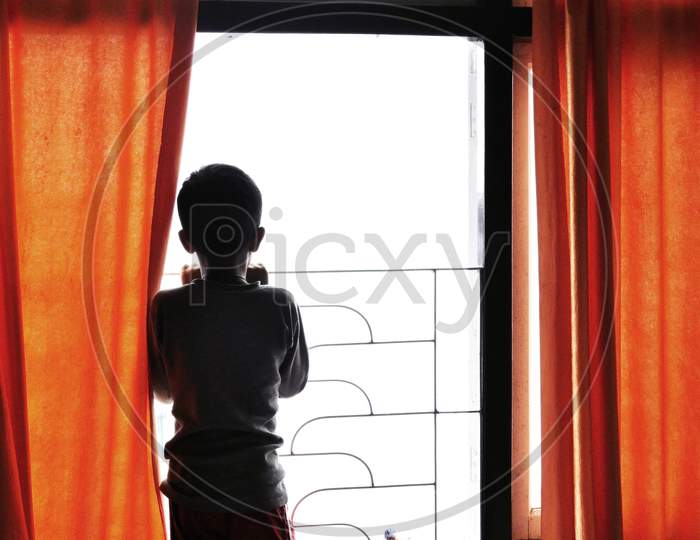 A Child Locked In The Room Or In Home Quarantine Looks To The Outer World Through The Window