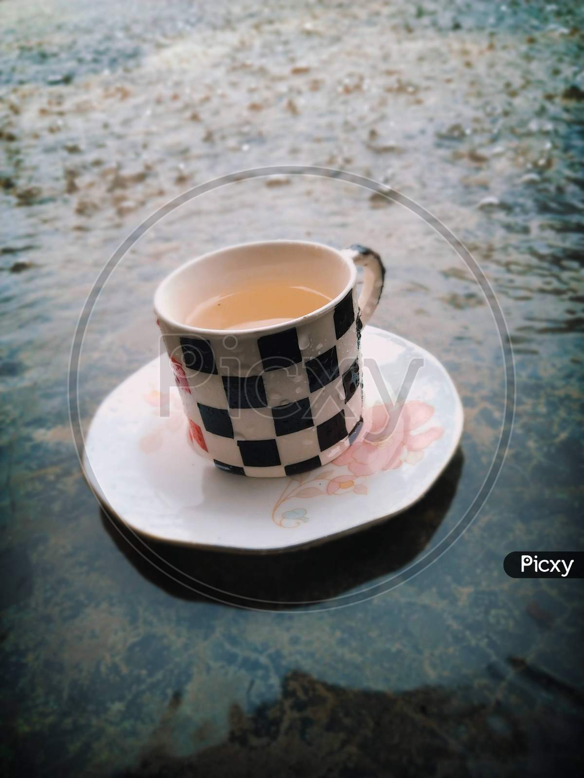 A cup of hot masala tea with rainy background.