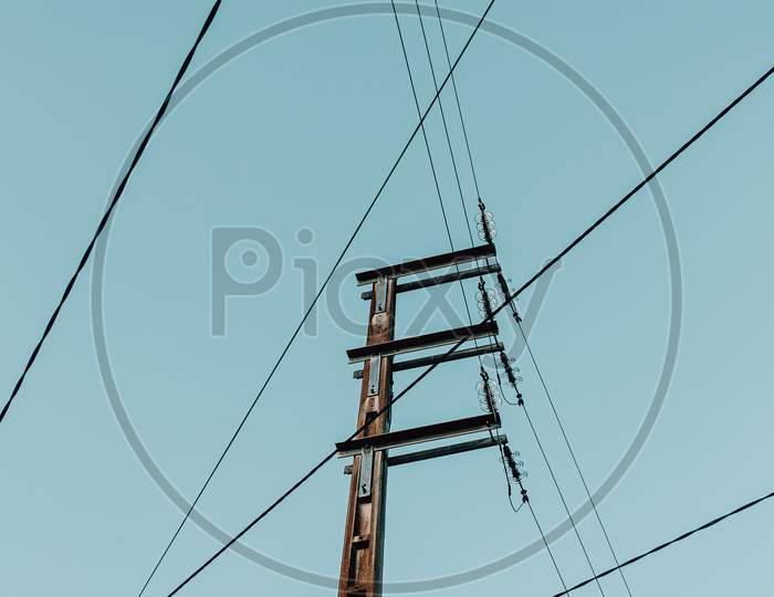 Electrical Post With A Lot Of Wires Crossing The Image And A Blue Sky