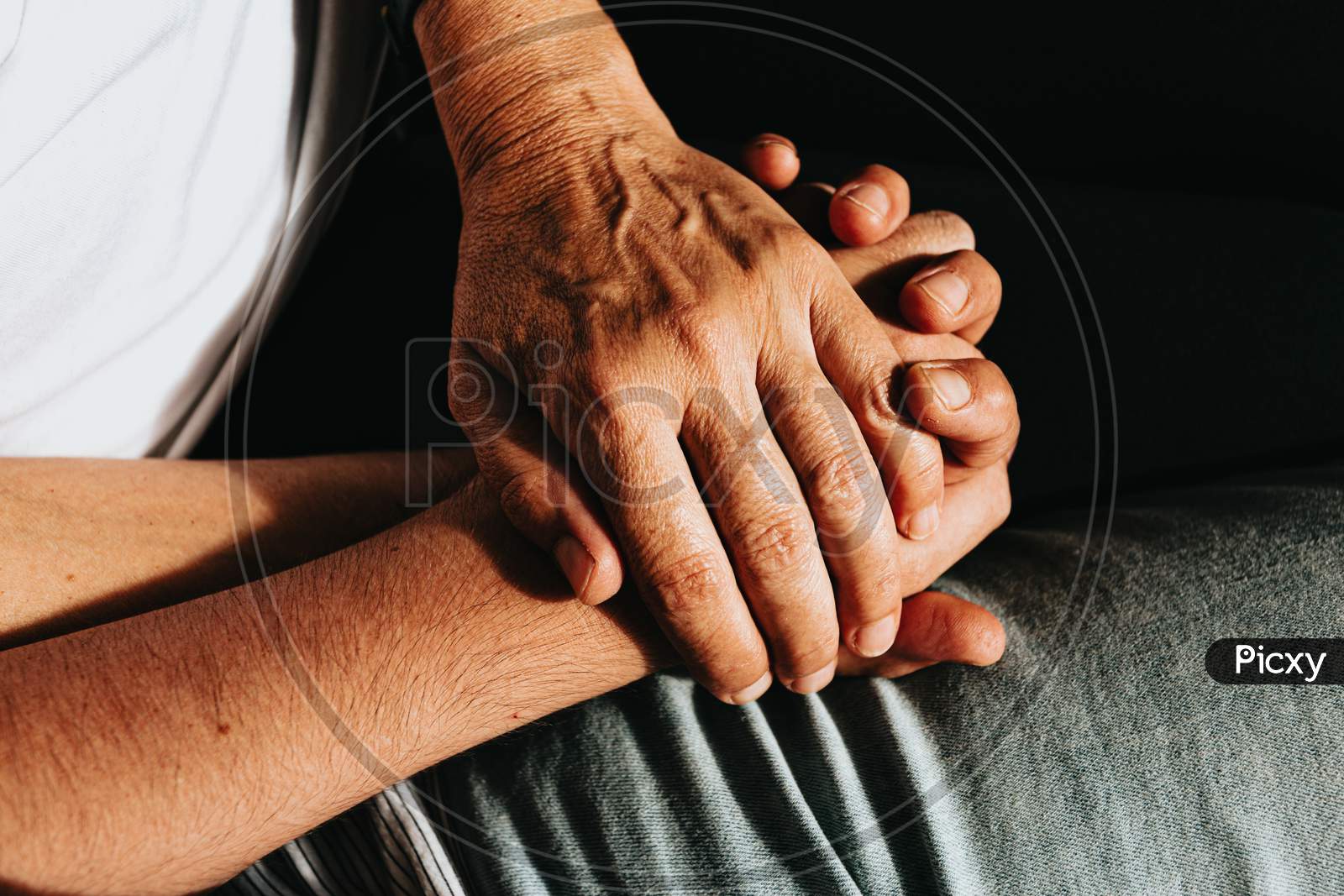 Close Up Of Two Old Hands Grabbing A Young Hand On Cinematic Tones