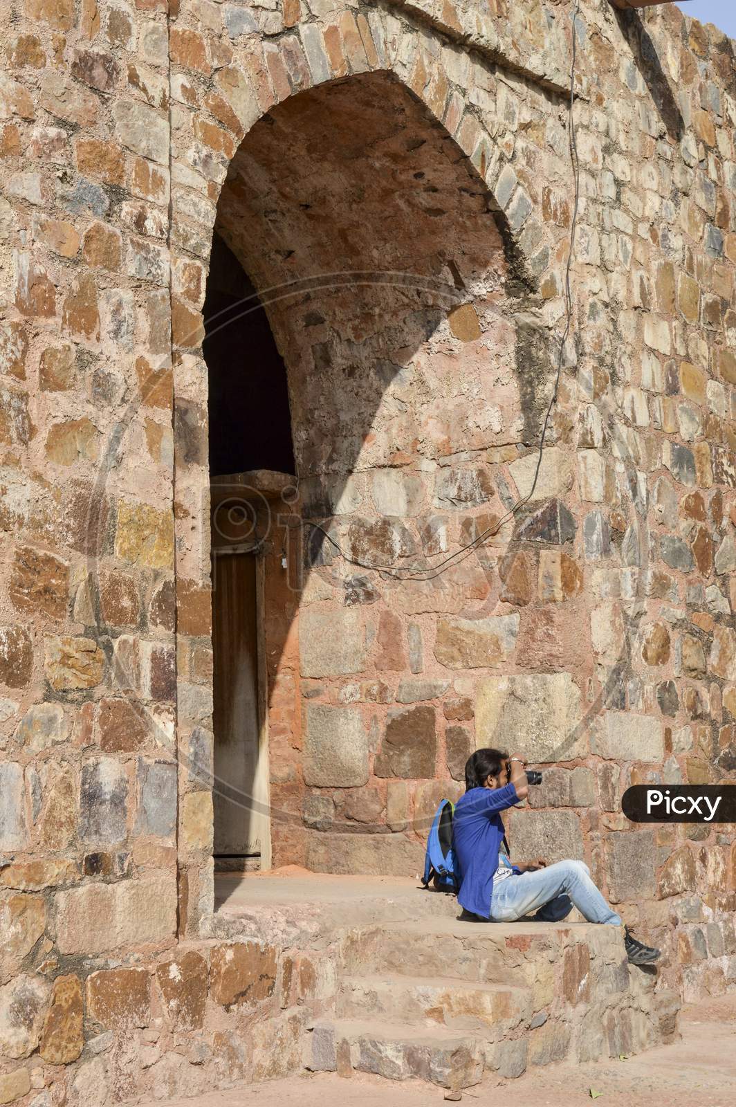 A Indian Boy Siting And Clicking Picture Of Old Fort Giving Pose For Fashion Shoot.