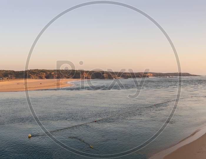 Where the river meets the sea. Wide panoramic image over Vila Nova de Milfontes in Alentejo at Portugal with sunset colors. Beauty of a summer day.