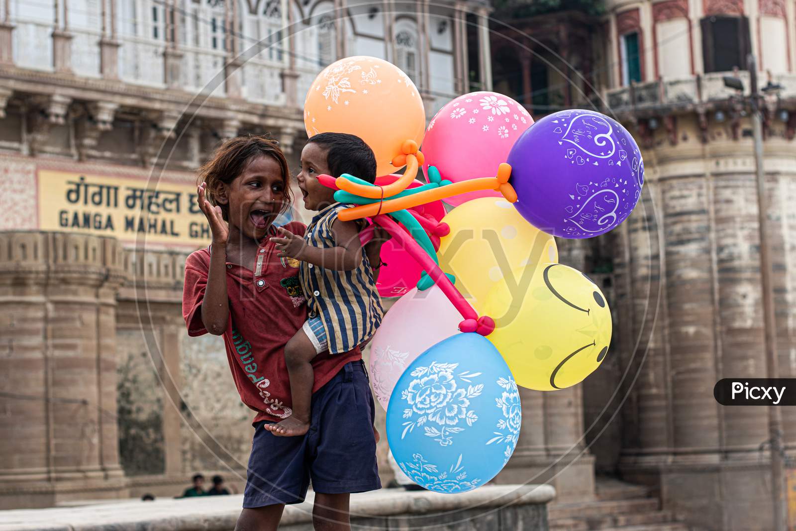 A little girl selling balloon on varanasi ghat and taking care her younger brother like a mother