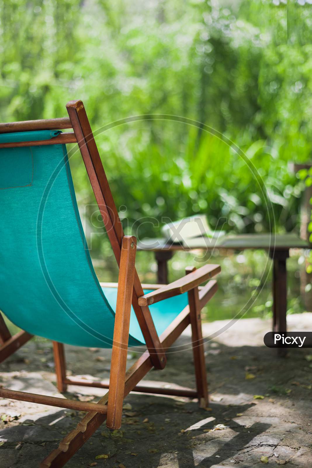 Wooden Beach Chair In The Garden And Some Books On The Table. Relaxing Place Concept.