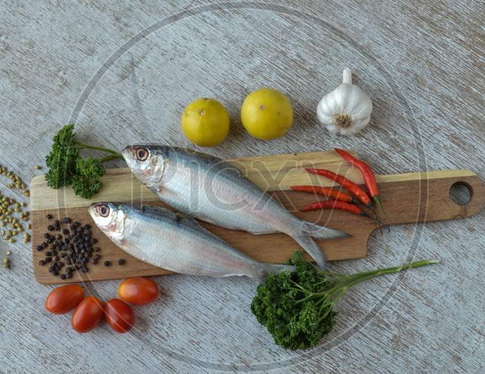 Delicious Fresh Fish With Aromatic Herbs, Spices And Vegetables Isolated On White Texture Wooden Table With Top View