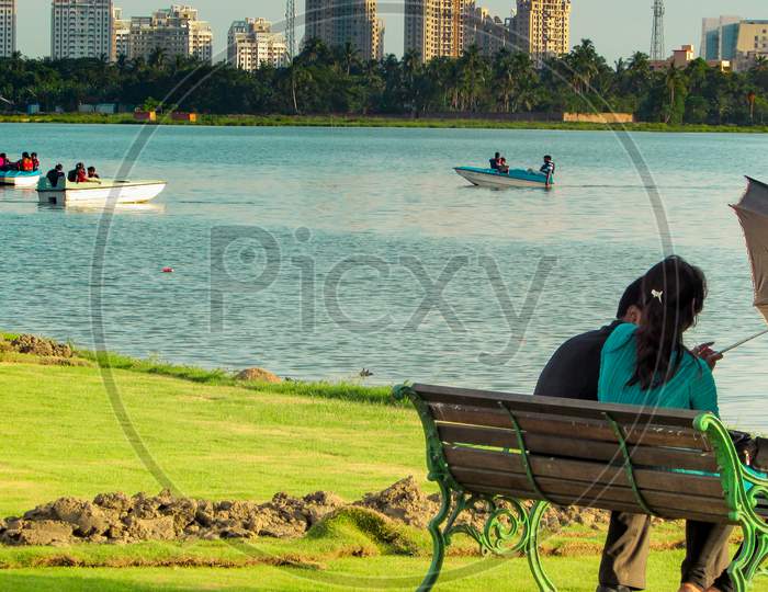 couple sitting with umbrella  near the lake