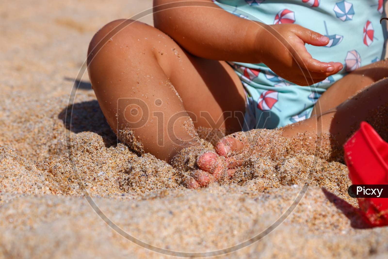 Little child with his feet in the sand playing on the beach.