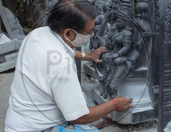 A Stone Sculpture Artist is seen giving Finishing touch to his creation of a Deity which is then  placed in a Hindu temple at Mysuru in Karnataka state of India.