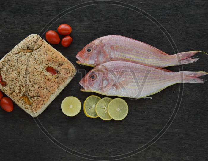 Fresh Uncooked Sea Fish With Lemon, Tomato, Bread Isolated On Rustic Wooden With Top View