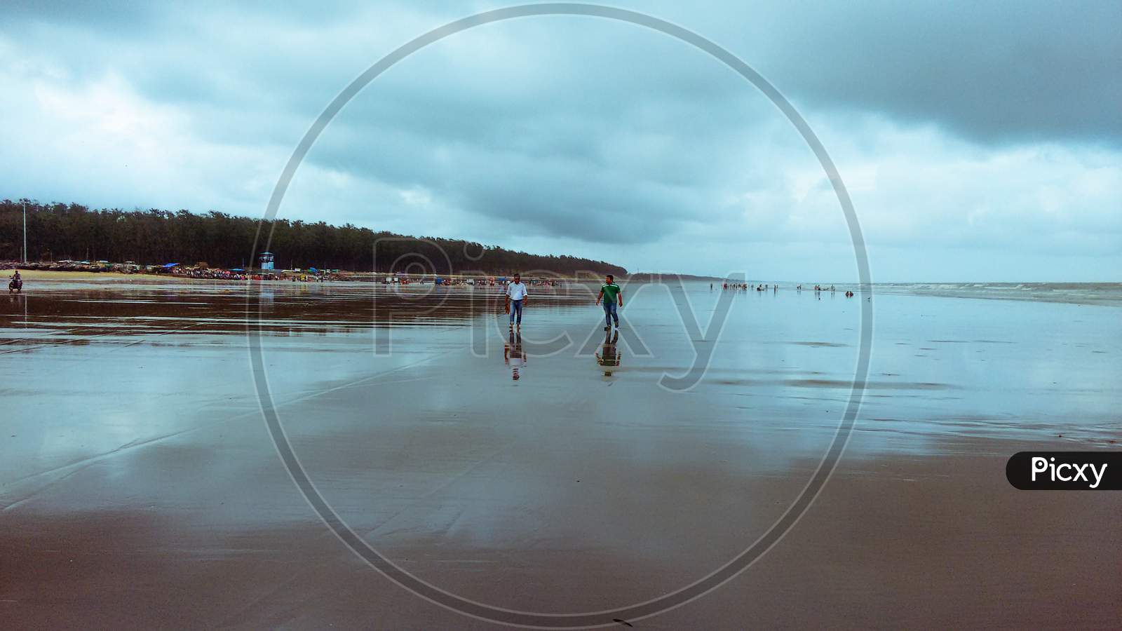 Two friends walking in the sea beach in cloudy weather