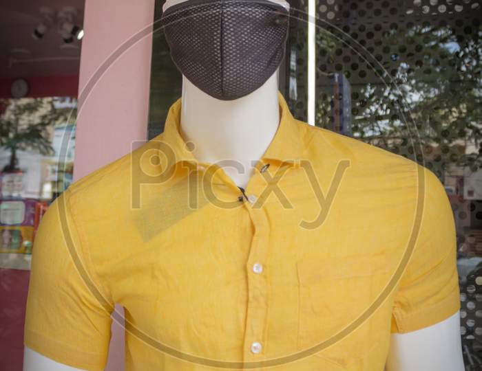 A Pretty picture of a Handsome Mannequin dressed in Yellow Cotton Shirt and a Black Face protection Mask at a street side store in Mysuru cityscape of Karnataka state in India.