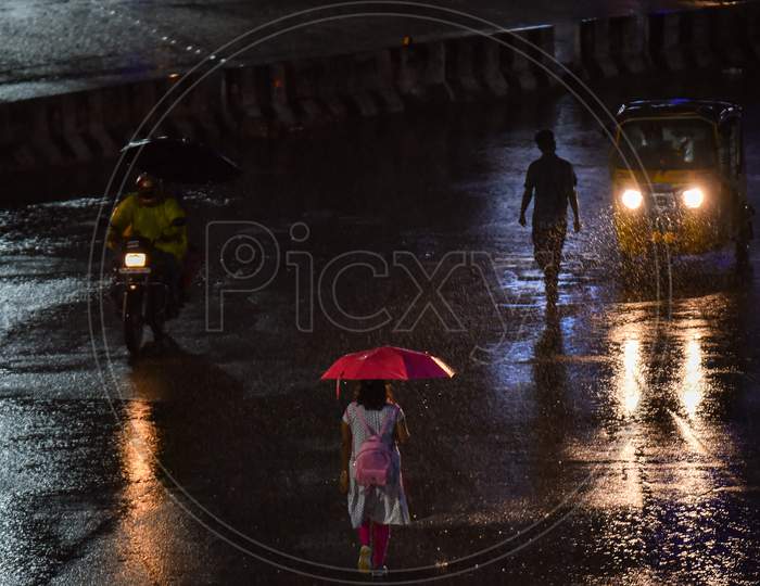 People walk on road as it rains heavily in Hyderabad, September, 16, 2020.