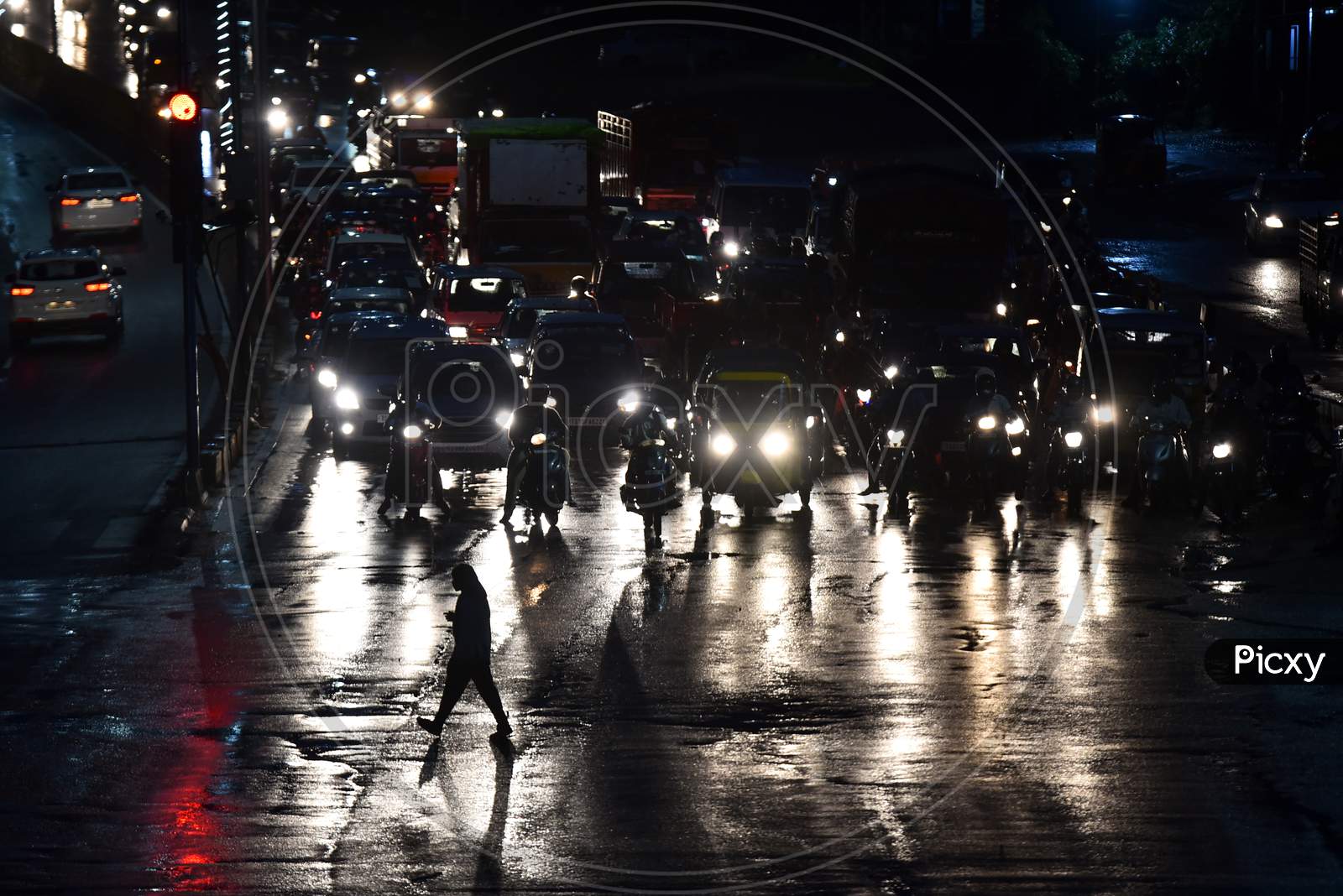 a man crosses road at a traffic signal as it rains heavily in Hyderabad, September 16,2020