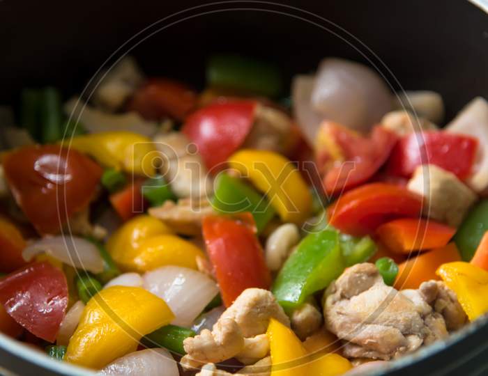 Close up chicken and vegetables saute in a pan