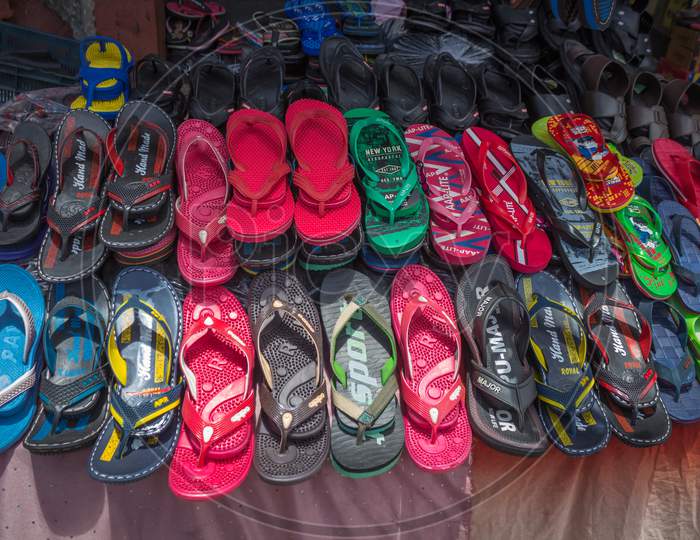 A Street Footwear vendor show casing the Slippers in Multi color arranged aesthetically in rural Mysuru cityscape of Karnataka state in India.