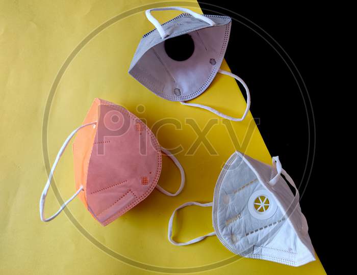 Inside View Of Three Kn-95 Face Masks In White,Grey And Orange Color. Isolated On Black And Yellow Background. Protection From Coronavirus Or Covid-19.