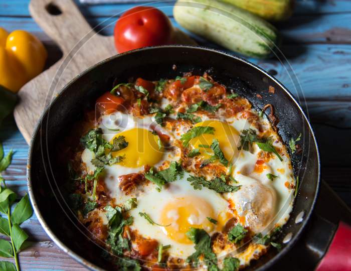 Vertical view of Shakshouka, a dish prepared with eggs, capsicum, tomatoes and onion in pan